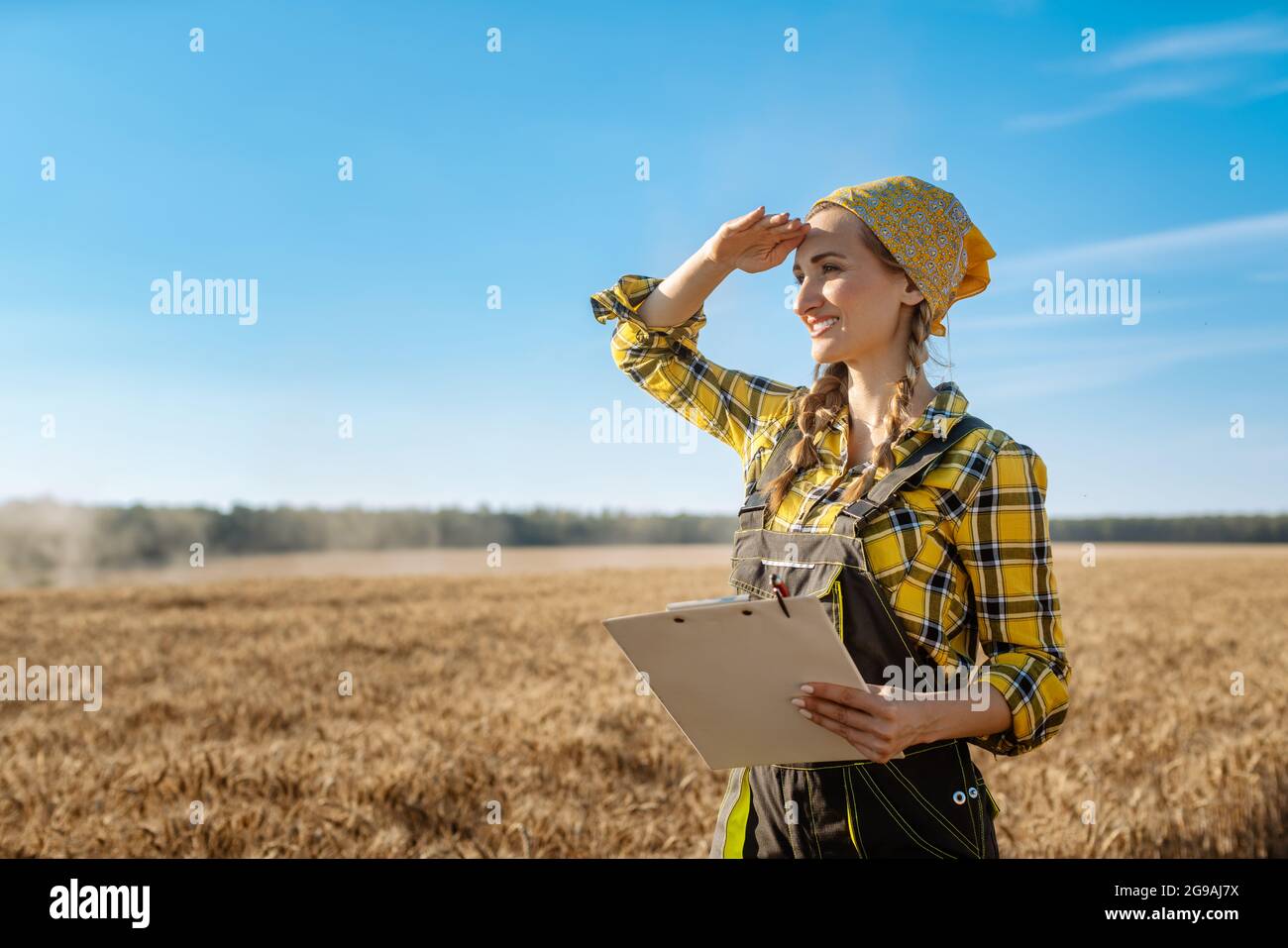 Farmer woman standing on grain field to be harvested Stock Photo