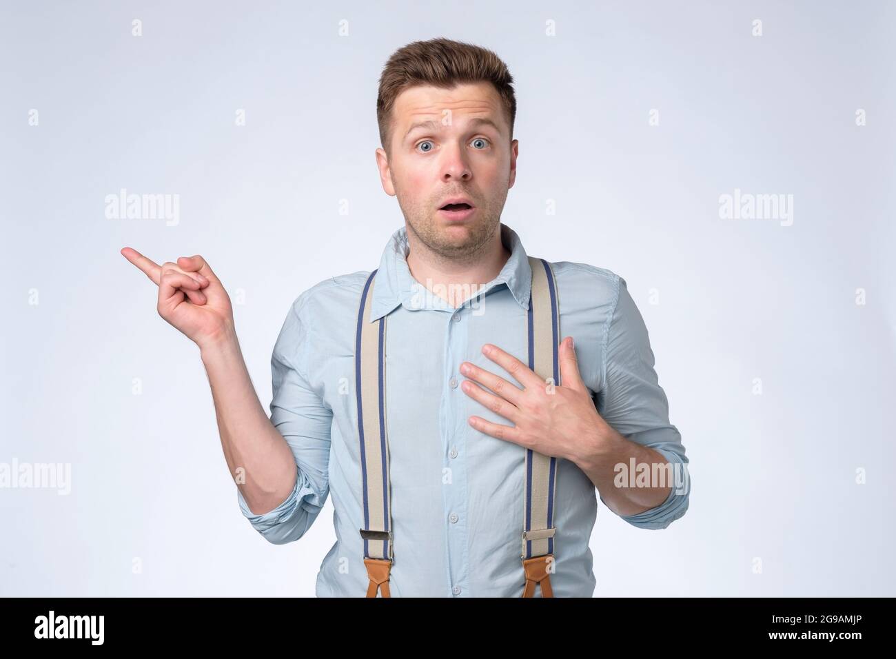 Young bewildered man pointing hands aside, looking camera. Stock Photo