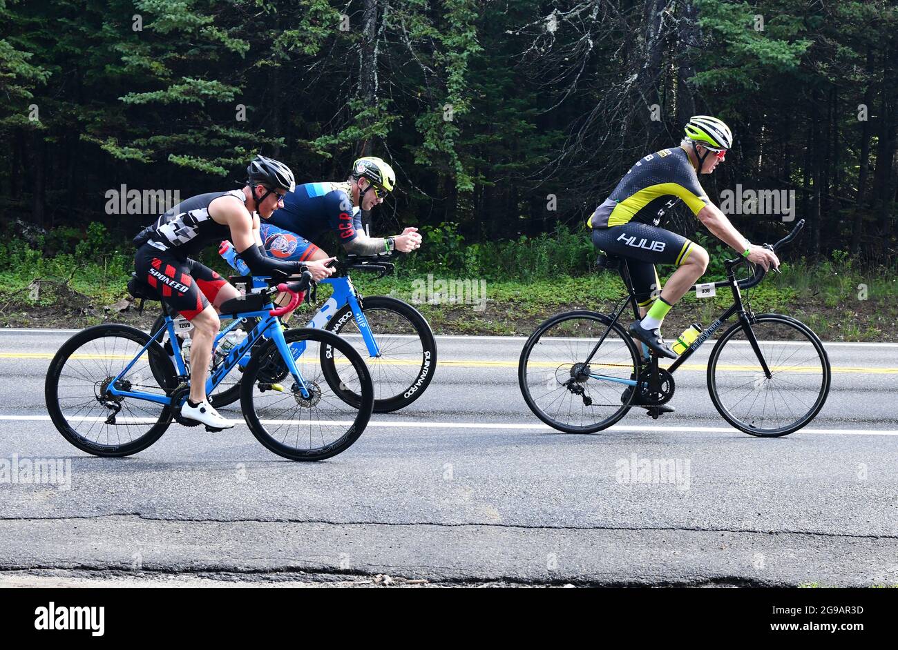 Ironman race participants engage in the grueling cycling portion of the long endurance triathlon race up and down the mountainous roads Stock Photo