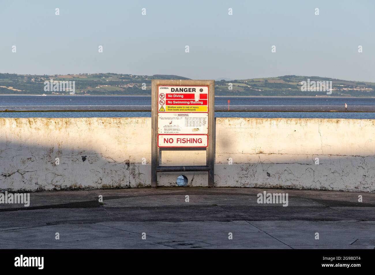 West Kirby, Wirral, UK. Danger sign next to the marine lake; no swimming, diving, or bathing; warning of weever fish with poisonous spines Stock Photo