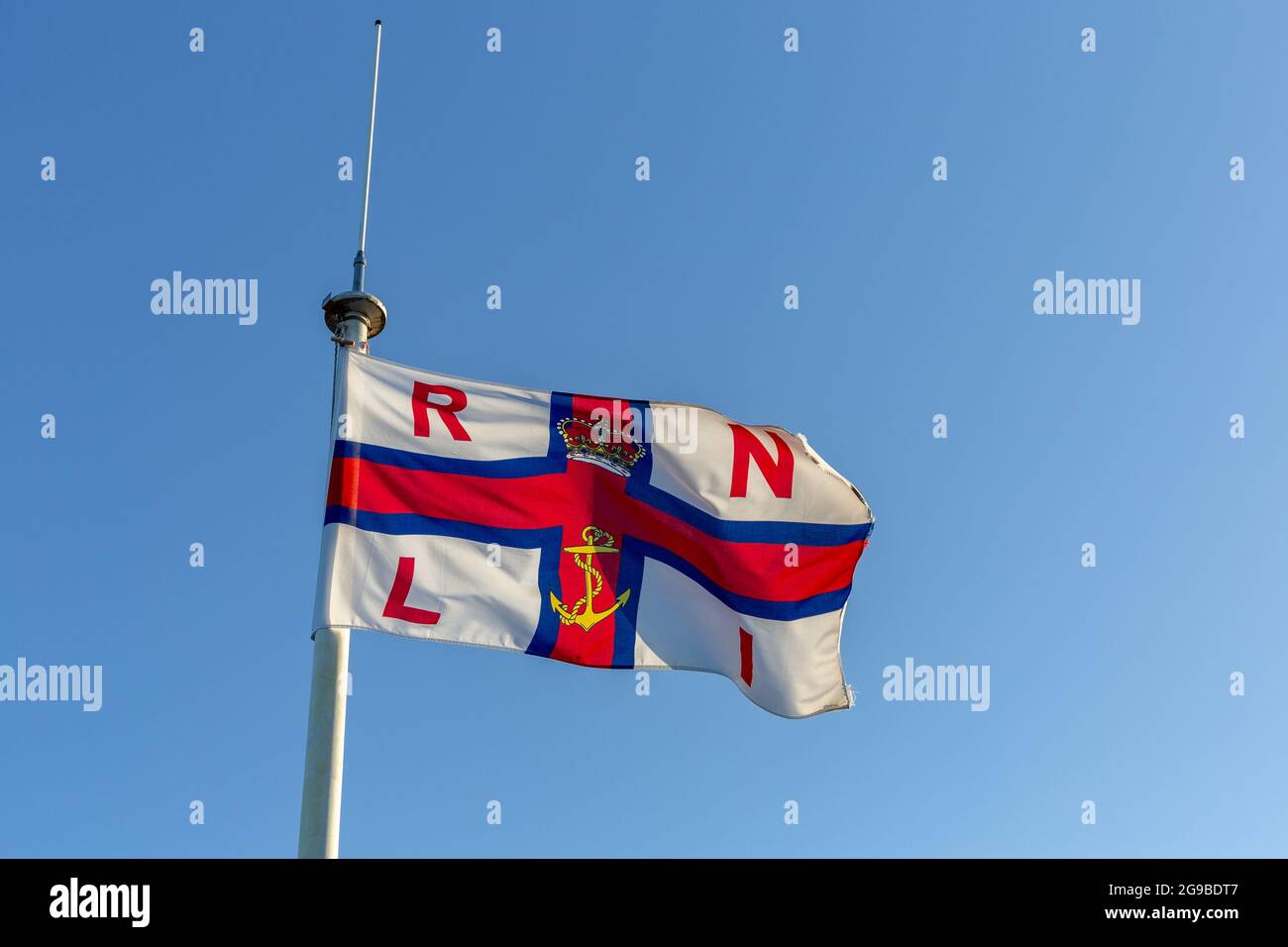 Royal National Lifeboat Institution flag, West Kirby, Wirral, UK. Fluttering in the breeze on an early summer morning. Stock Photo