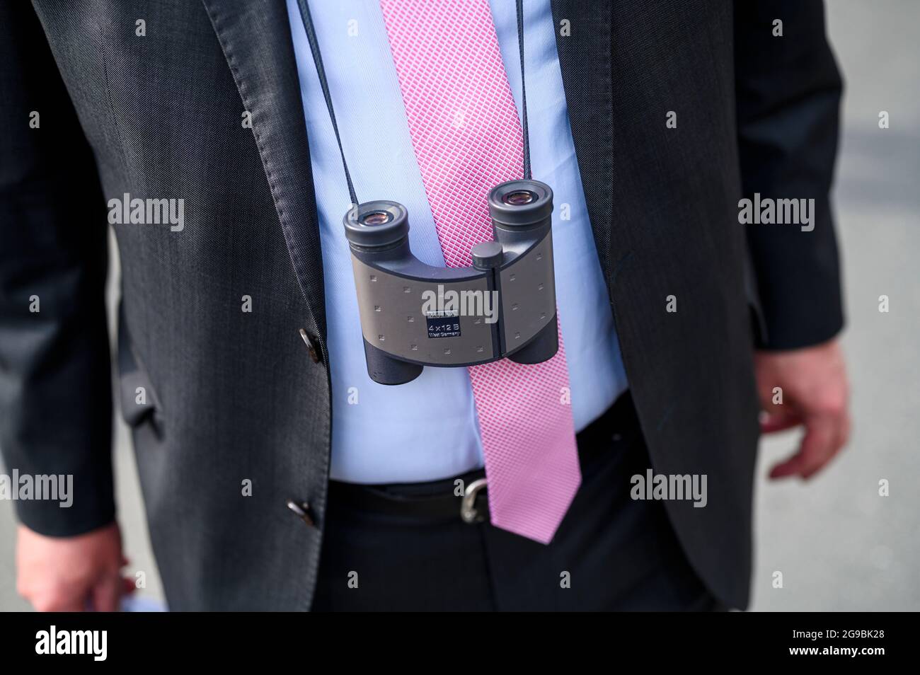 Bayreuth, Germany. 25th July, 2021. Opening of the Richard Wagner Festival 2021 with a new production of the opera 'The Flying Dutchman'. An opera guest wears binoculars around his neck in front of the Festspielhaus on the Grüner Hügel. Credit: Daniel Vogl/dpa/Alamy Live News Stock Photo