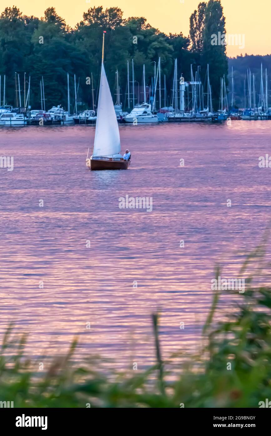 Berlin, Germany - July 10, 2019: Sailing boat on purple water in Wannsee Lake at sunset Stock Photo