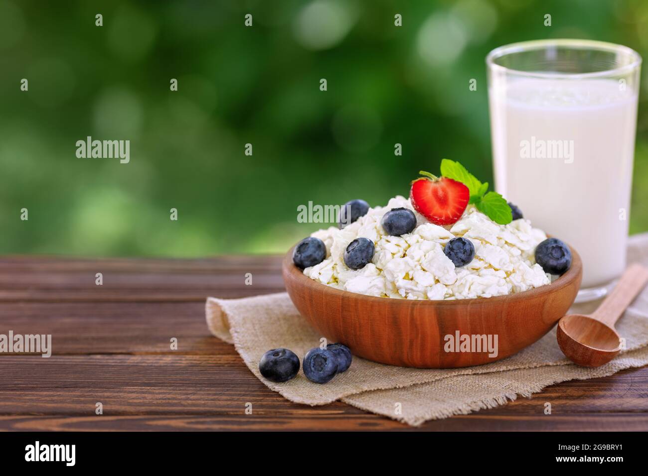 yogurt in glass and cottage cheese with fresh blueberries on table outdoors Stock Photo