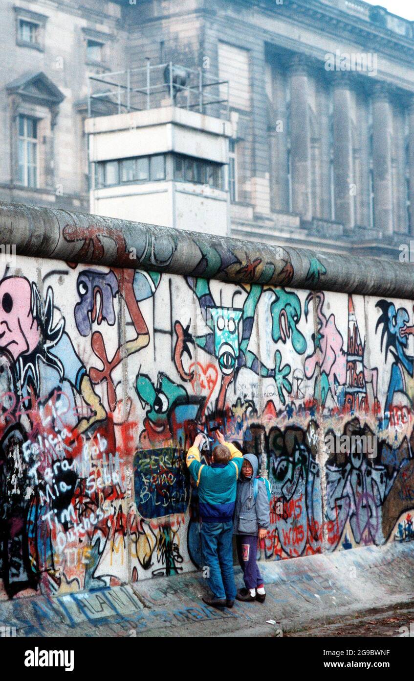 West German children attempt to chip off a piece of the Berlin Wall as a souvenir. A portion of the Wall has already been demolished at Potsdamer Platz, 1989 Stock Photo