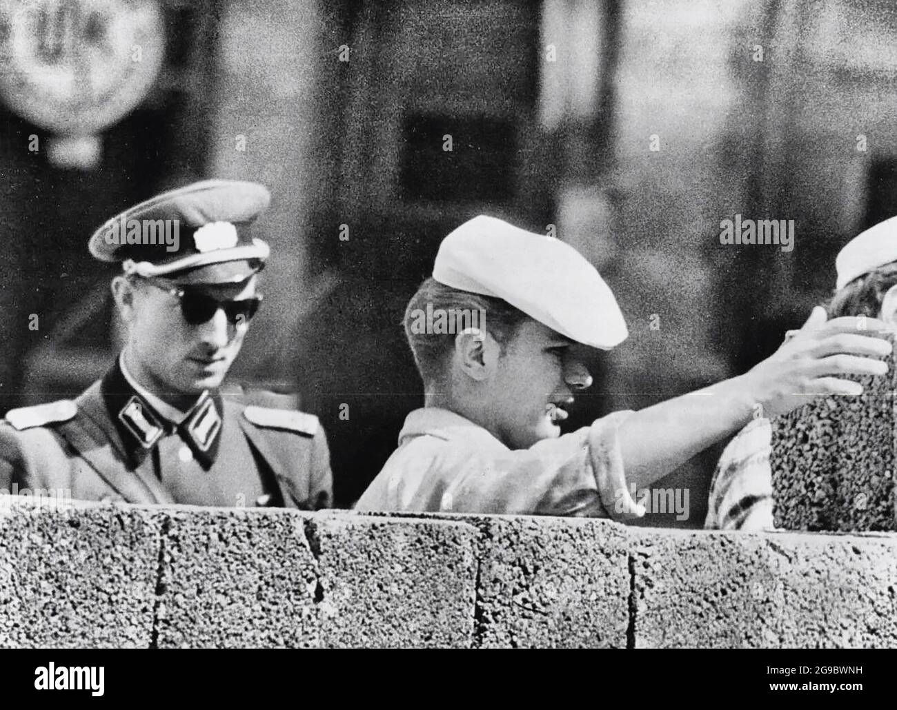 Watched Carefully By A Communist Policeman, An East Berlin Mason Doubles the Height of the Concrete Barricade Along the Border Facing West Berlin, 1961 Stock Photo