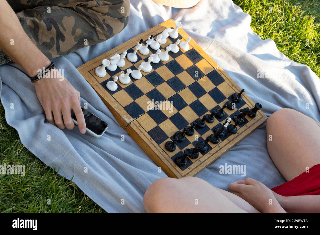 Teenagers playing chess on green grass in the park. Top view. Selective focus Stock Photo