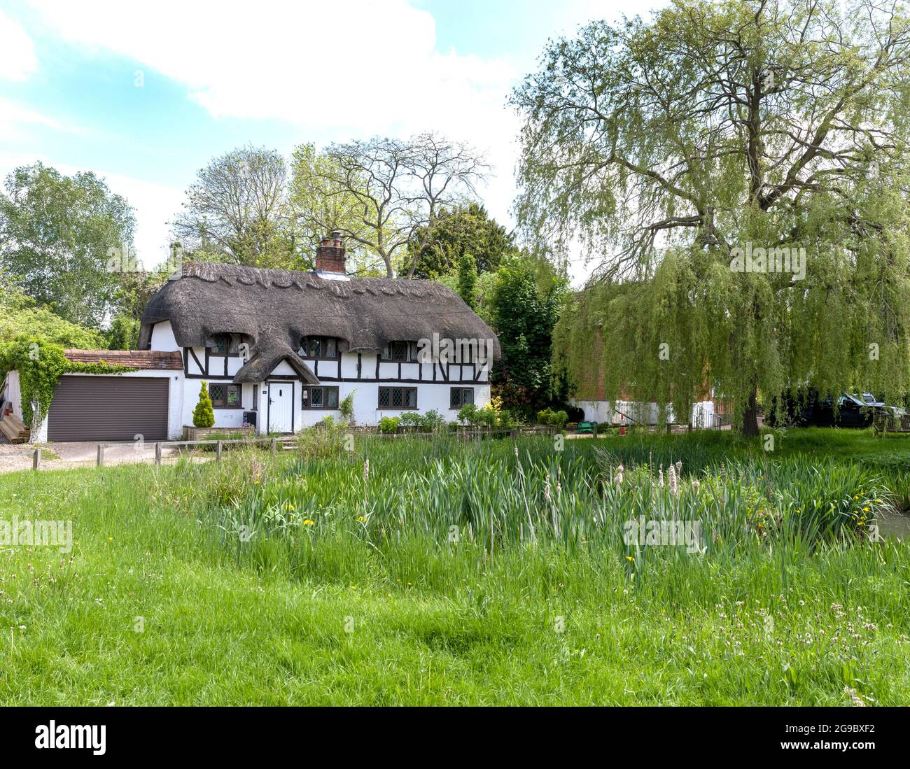 The Duck pond in the centre of the village Oakley with traditional thatched cottages in the background, Oakley, Hampshire, England, UK. Stock Photo