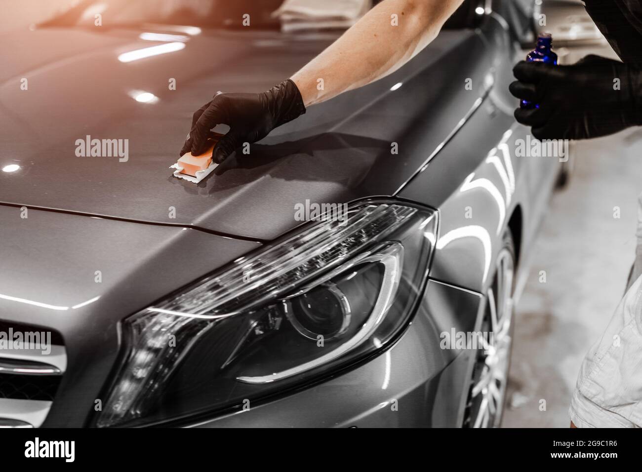 Car detailing and polishing concept with male worker. Polishing gray