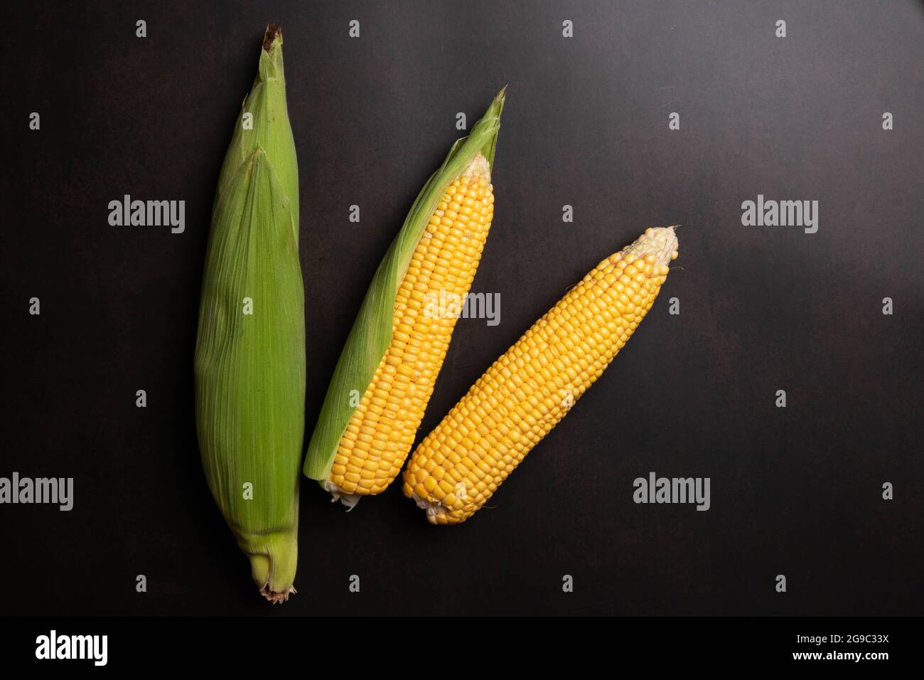 Fresh corn cobs on flat black background Stock Photo