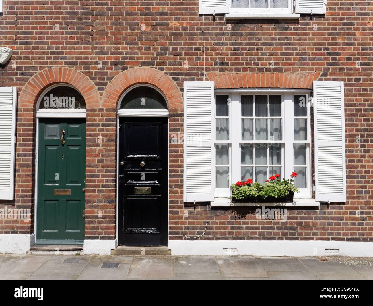 London, Greater London, England, June 12 2021: Green and black front doors of residential properties with a window box full of plants and flowers. Stock Photo