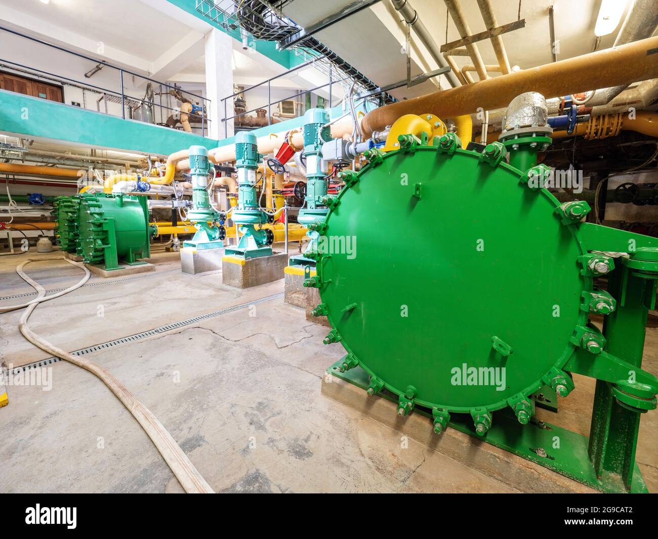 Green water tank. Big heat exchanger in an industrial cellar. Lots of pipes and pumps. Stock Photo