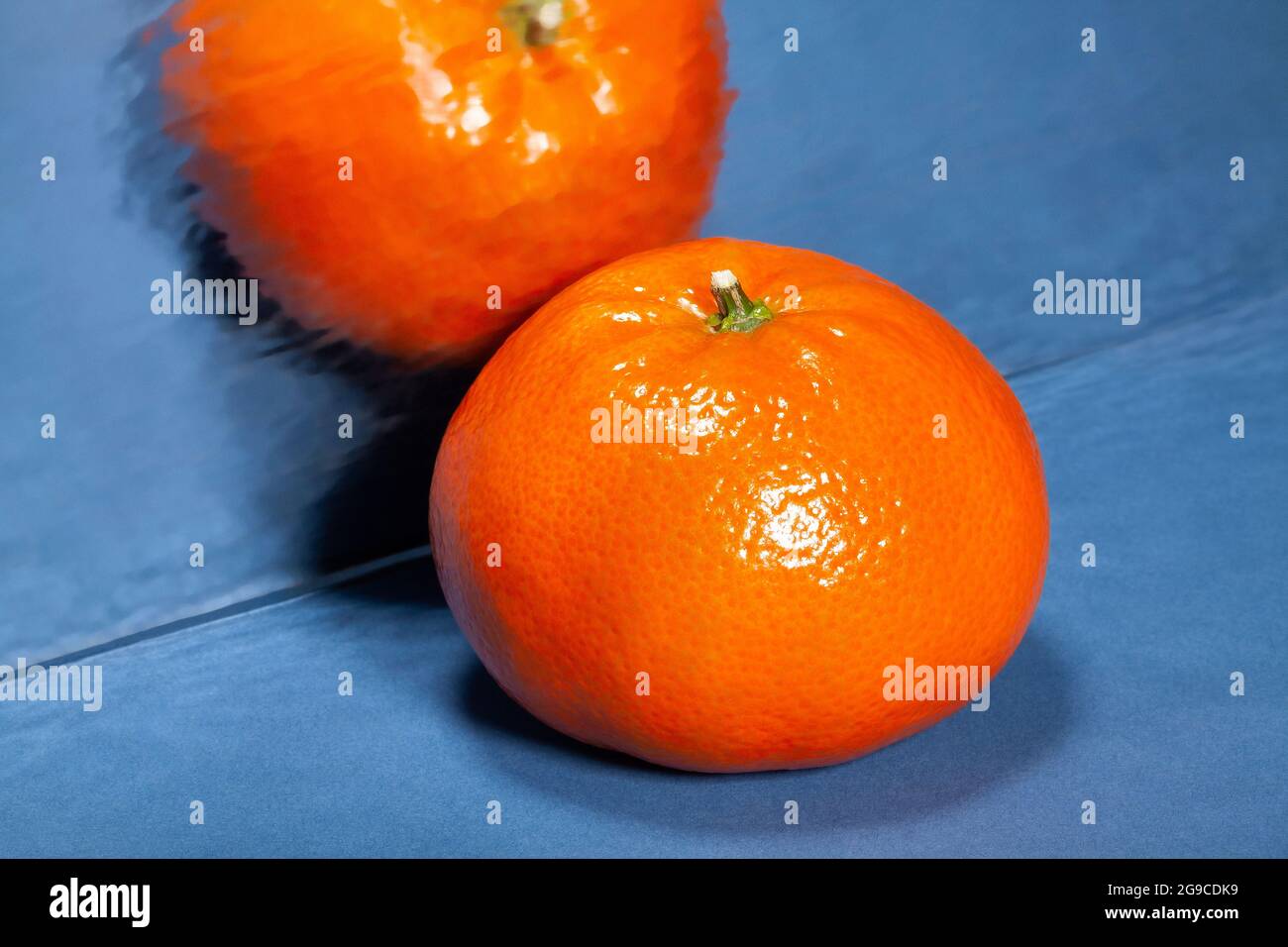 mirrored tangerine on blue background Stock Photo
