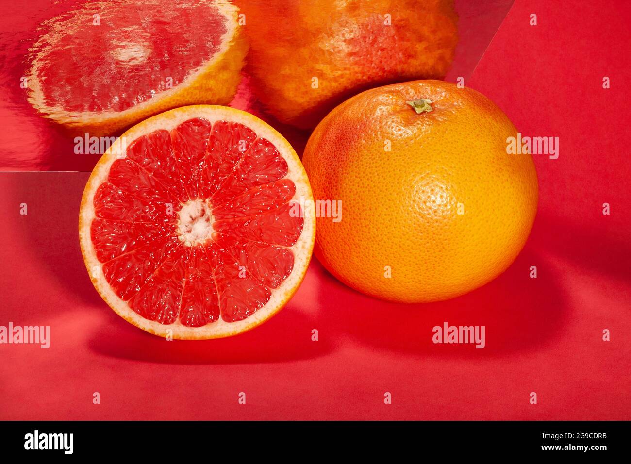 sliced mirrored grapefruit on red background Stock Photo