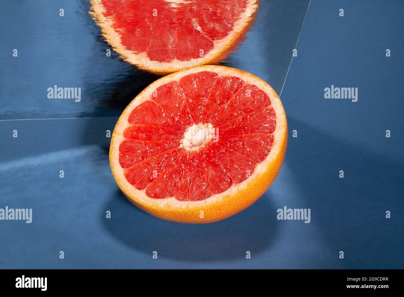 sliced mirrored grapefruit on blue background Stock Photo