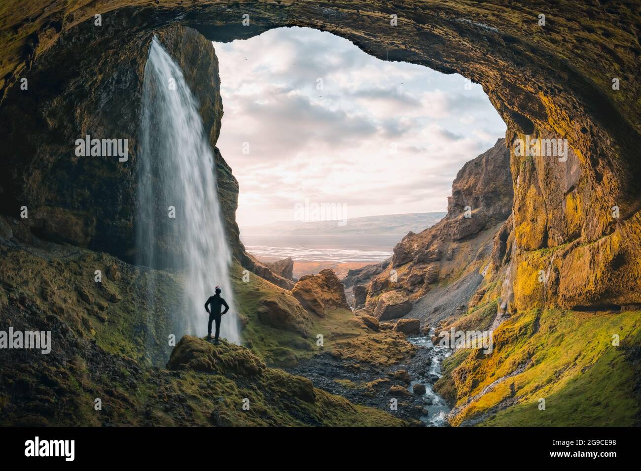 Adventurous young man standing behind waterfall in the highlands of Iceland. High quality panorama photo Stock Photo