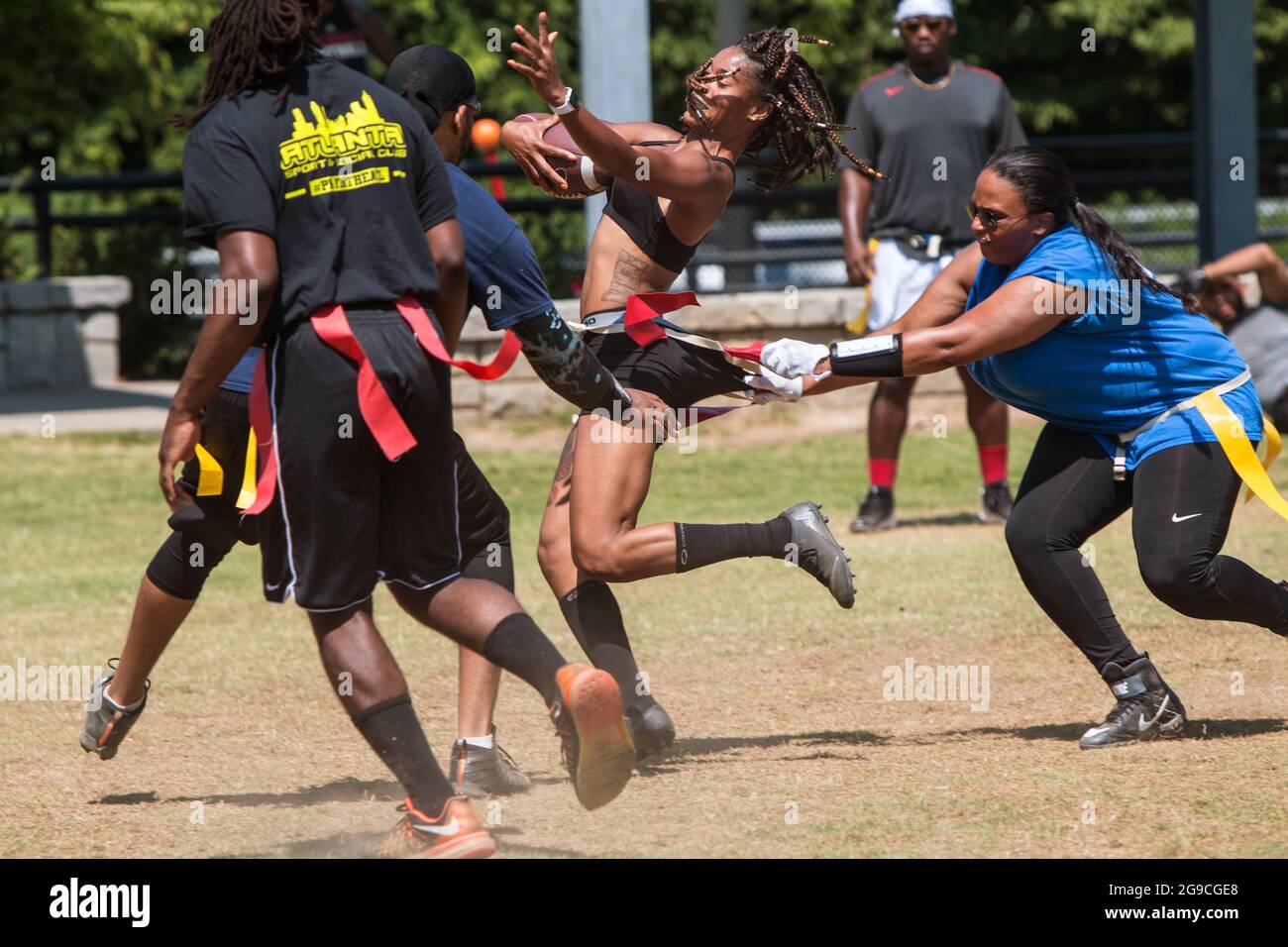 Atlanta, GA, USA - June 1, 2019:  A woman strenuously pulls the flags of a female opponent carrying the ball in a rec league flag football game. Stock Photo