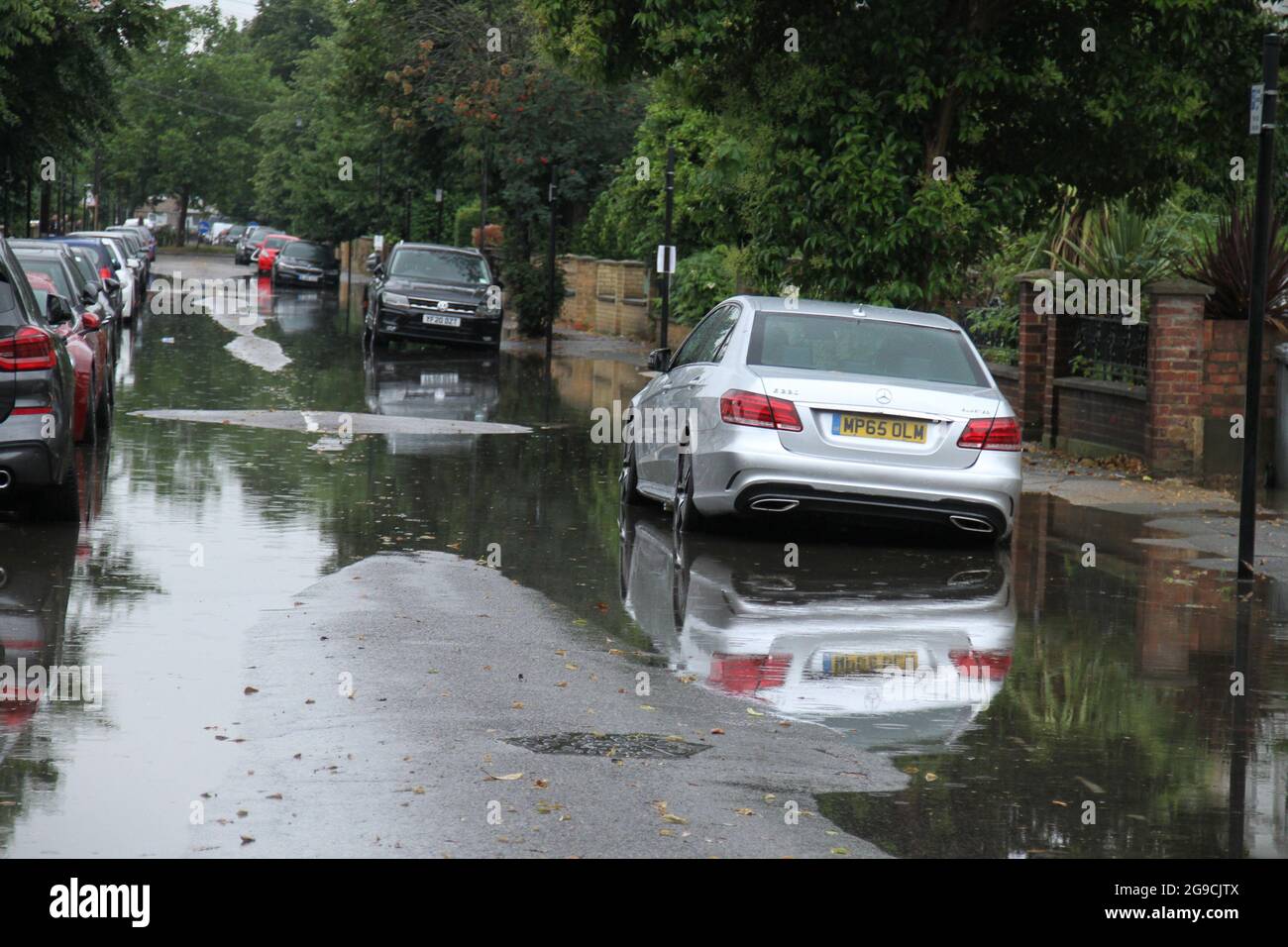Vehicles seen parked on a flooded street in a suburb in East London following flash flooding ?today afternoon.? Extreme heat in the previous week has given way to cooler temperatures and stormy weather in England.? ?An amber thunderstorm warning is in place for much of south-east England?.? Stock Photo