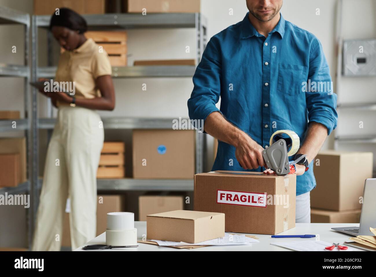 Cropped portrait of young man packing boxes at warehouse with Fragile sticker, copy space Stock Photo