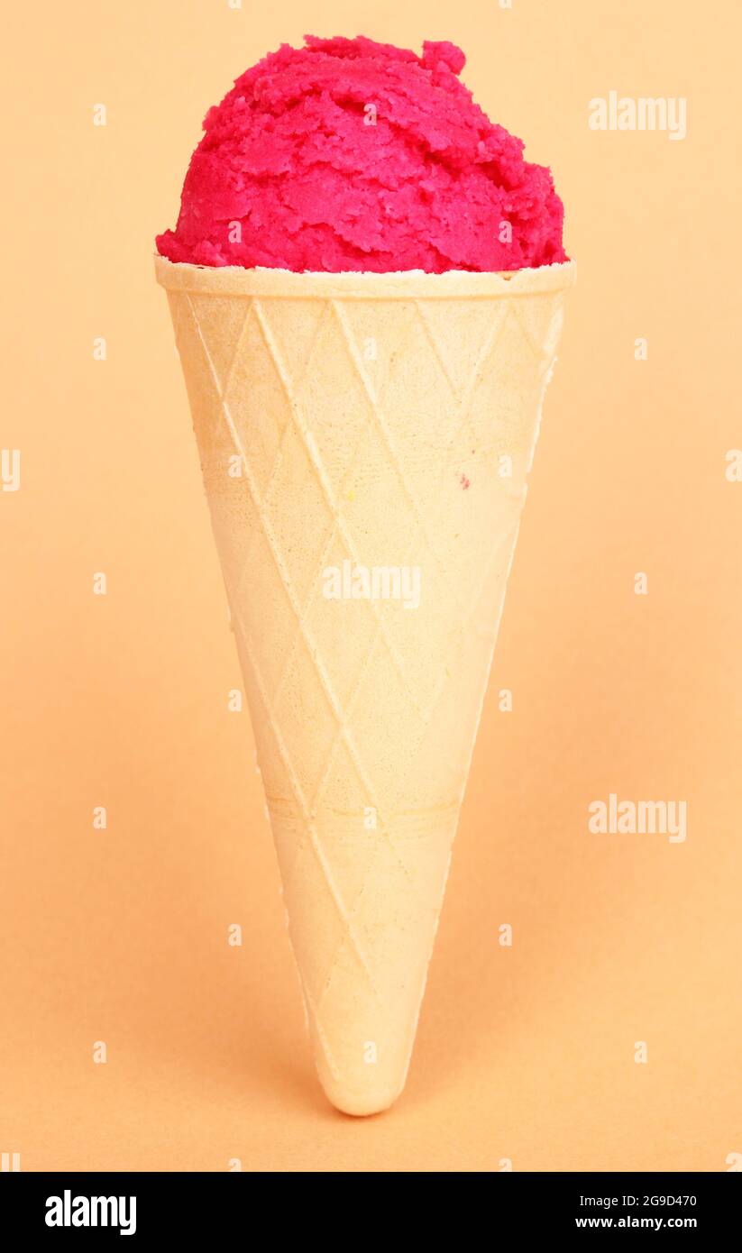 Scoop of the strawberry ice cream in the waffle cone on coral ...