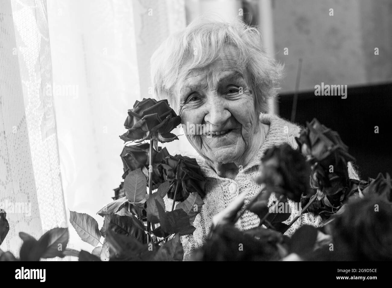 An senior woman with flowers in the her house. Black and white photo ...