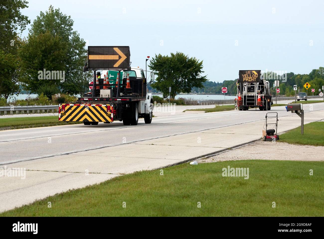 Road maintenance trucks and crew painting yellow traffic control lines on highway. Stock Photo