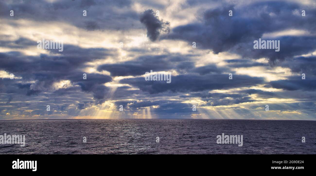 Sun rays passing through dark clouds. The unpredictable drama of the sky. A view from a tourist cruise ship sailing in the North Pacific Ocean. June 2 Stock Photo