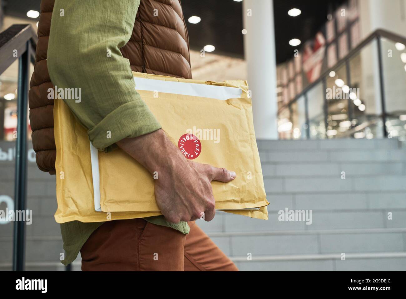 Close up of unrecognizable delivery man holding parcels while entering office building, copy space Stock Photo