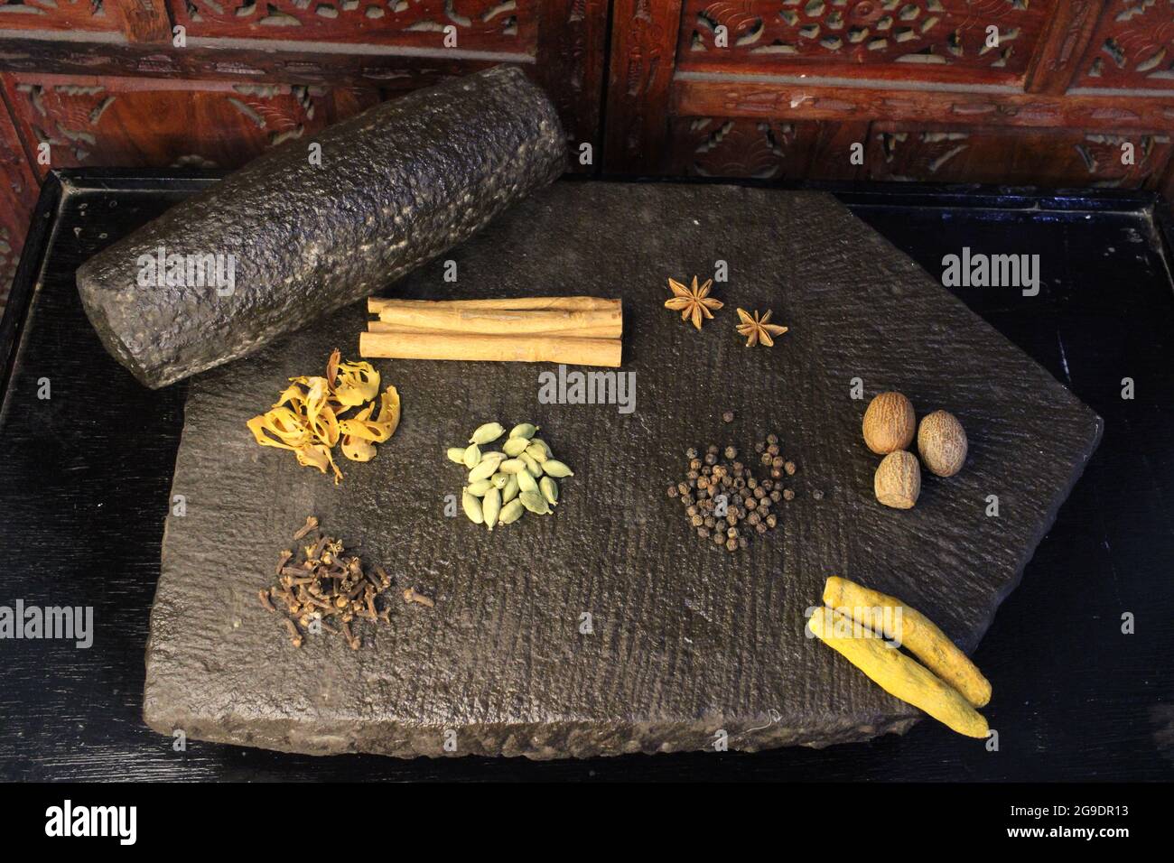 Most common and flavourful Indian Spices. Spices used in Indian food. Spices in traditional masala grinding stone Stock Photo
