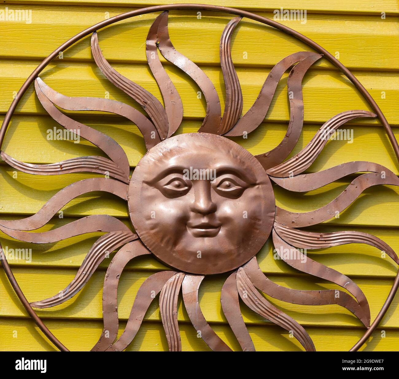 Bronze metal sun decoration on yellow wall of the house. Street view, travel photo, selective focus. Stock Photo