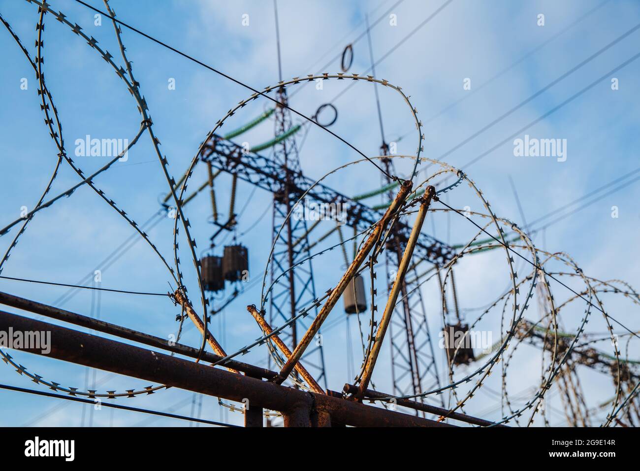 Barbed wire fence against the background of high voltage power lines. Stock Photo
