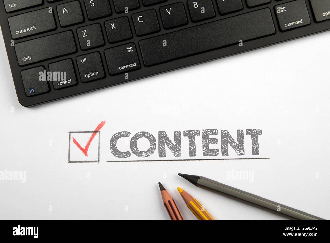 CONTENT. Computer keyboard and pencils on a white table. Stock Photo