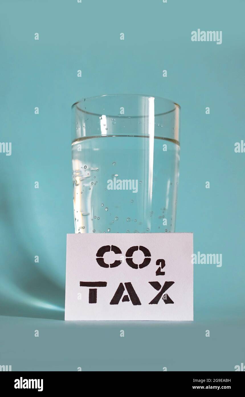 A glass of sparkling water and a card with the inscription Carbon tax  Stock Photo