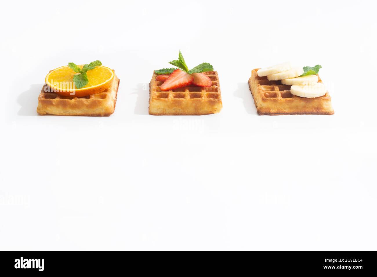 Belgium waffles with strawberry, banana and orange with syrup on white Stock Photo