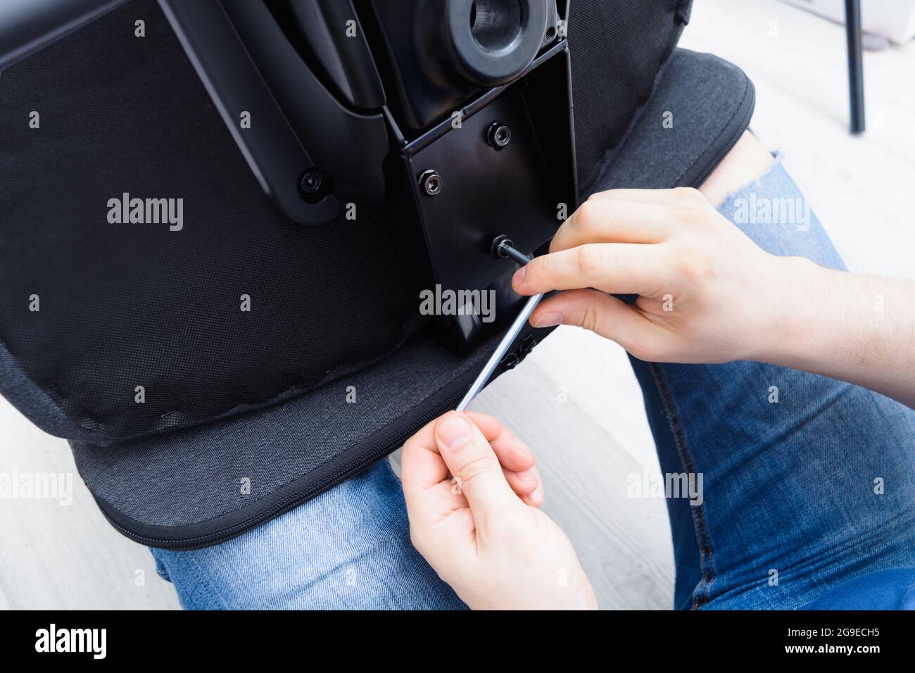 Caucasian man hands screw chair back. Assembling office chair indoors. Step 12 Stock Photo