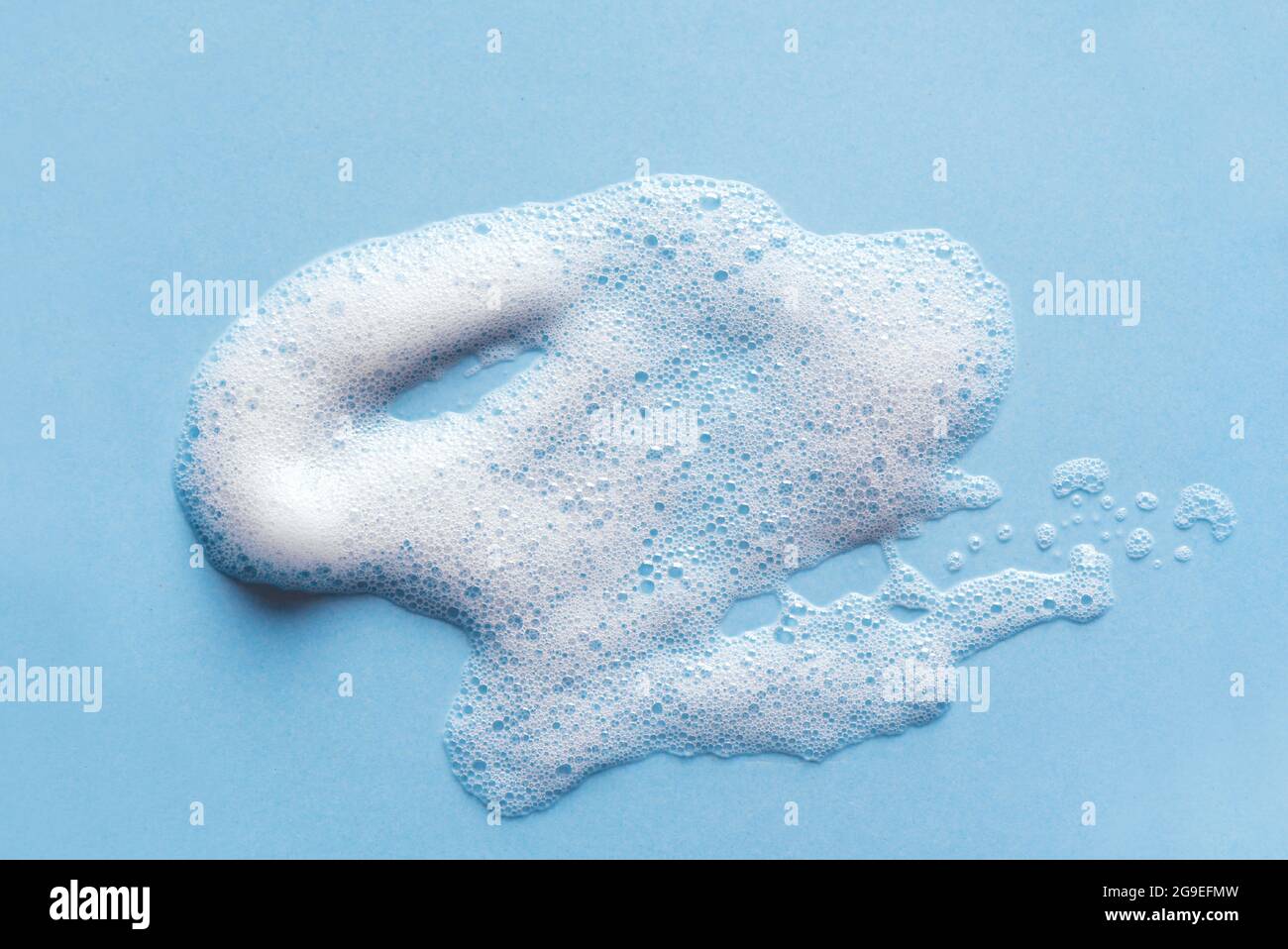 Face cleansing mousse sample. White cleanser foam bubbles on blue
