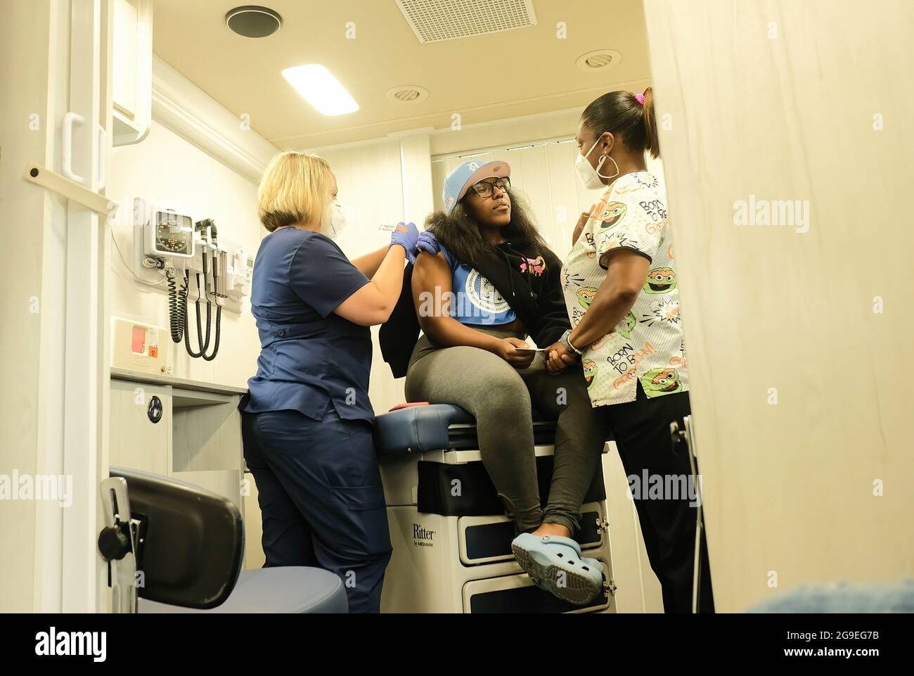 Detroit, Michigan, USA. 21st July, 2021. Health Care Workers from the Detroit Health Department administer a dose of the Pfizer Covid-19 vaccine to a patient during mobile vaccination clinic at East English Village High School.Vaccination Clinics are being held at various dates through the rest of July and into August at 3 different public high schools in Detroit, Michigan. The clinics are part of an effort between the Detroit Health Department and the Detroit Public Schools Community District to administer as many vaccines as they can prior to the coming school year, and to try and c Stock Photo