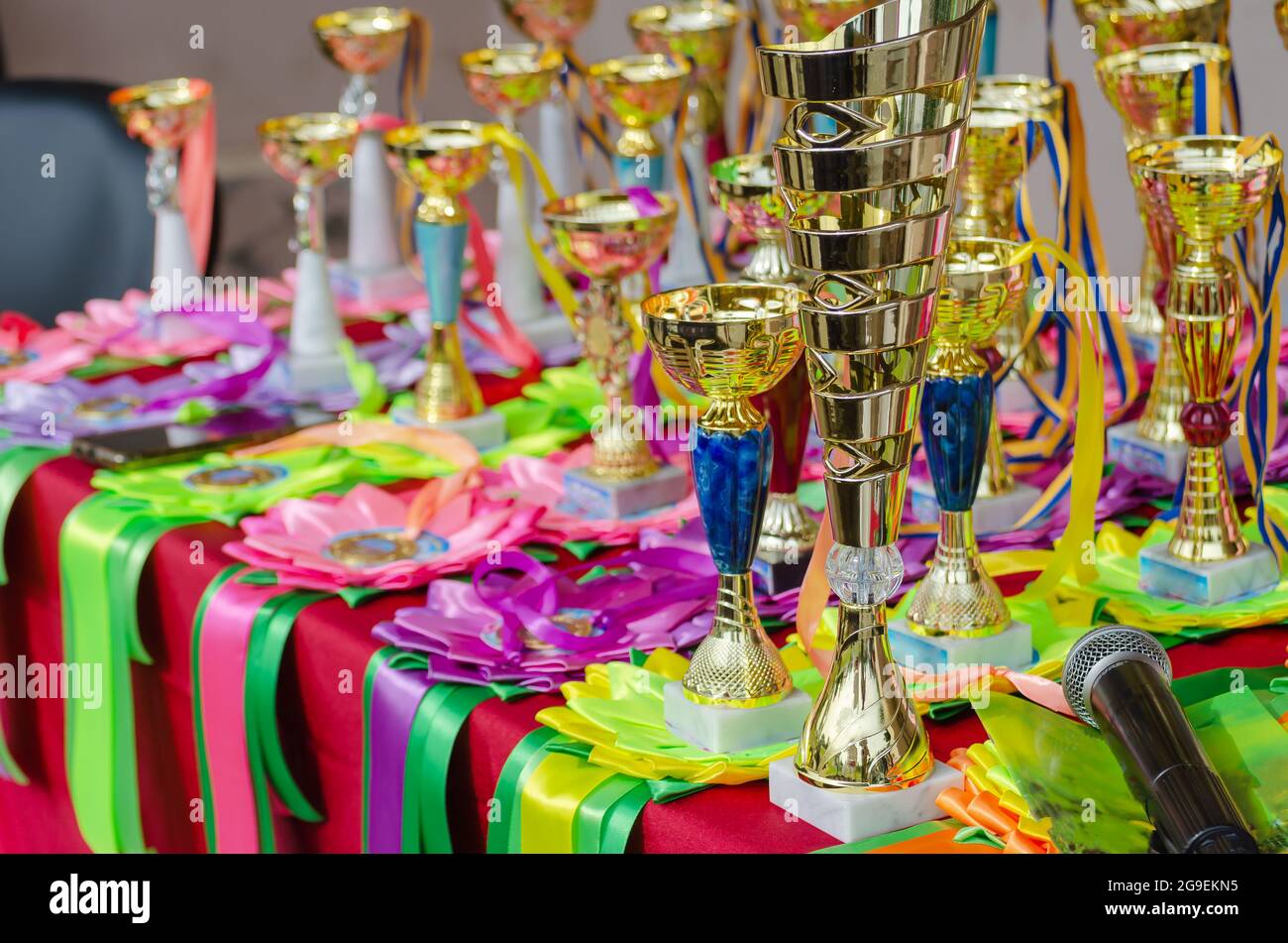 Various sports trophies, awards ribbons and a microphone on the table