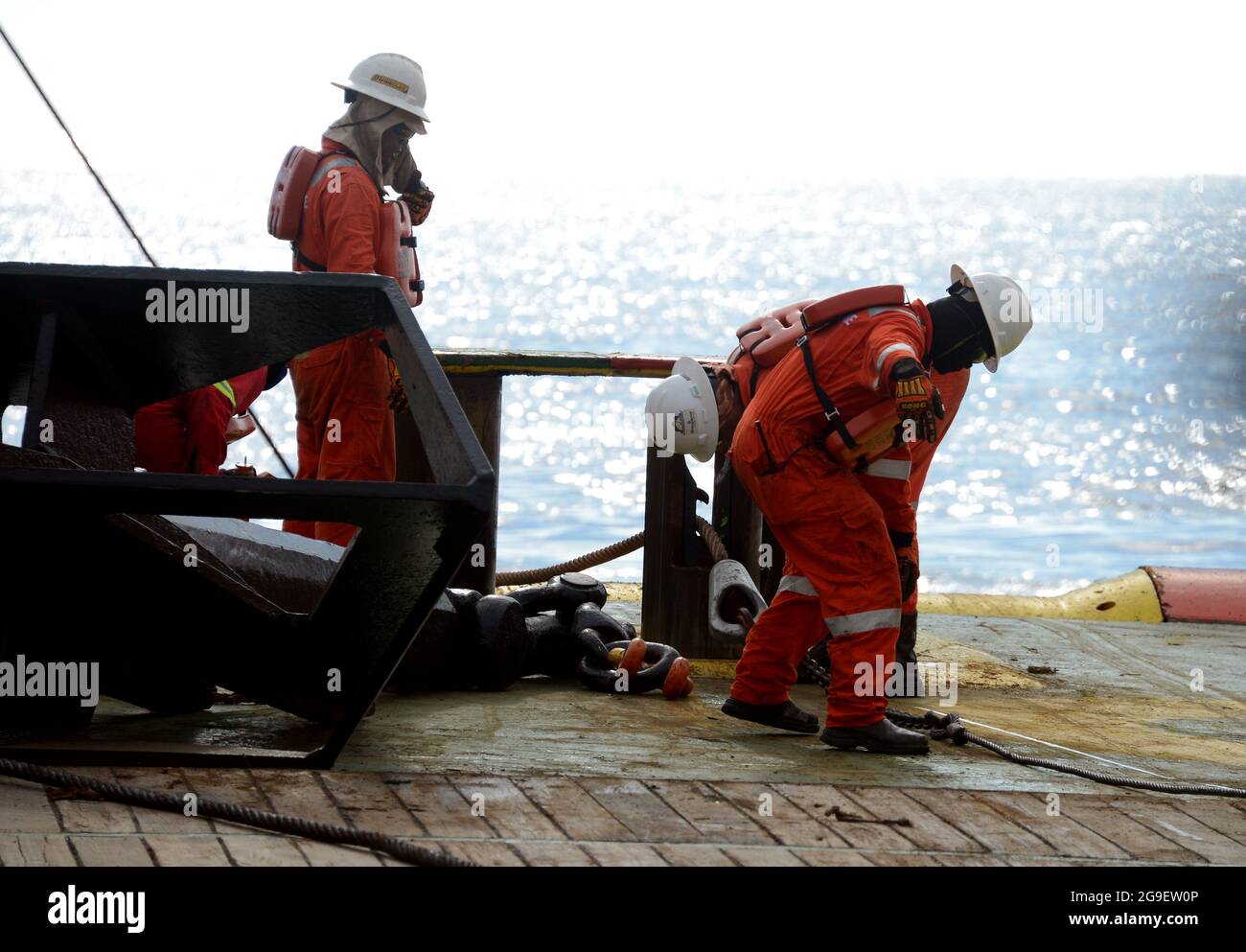 marine crew working on deck during anchor handling operation at sea