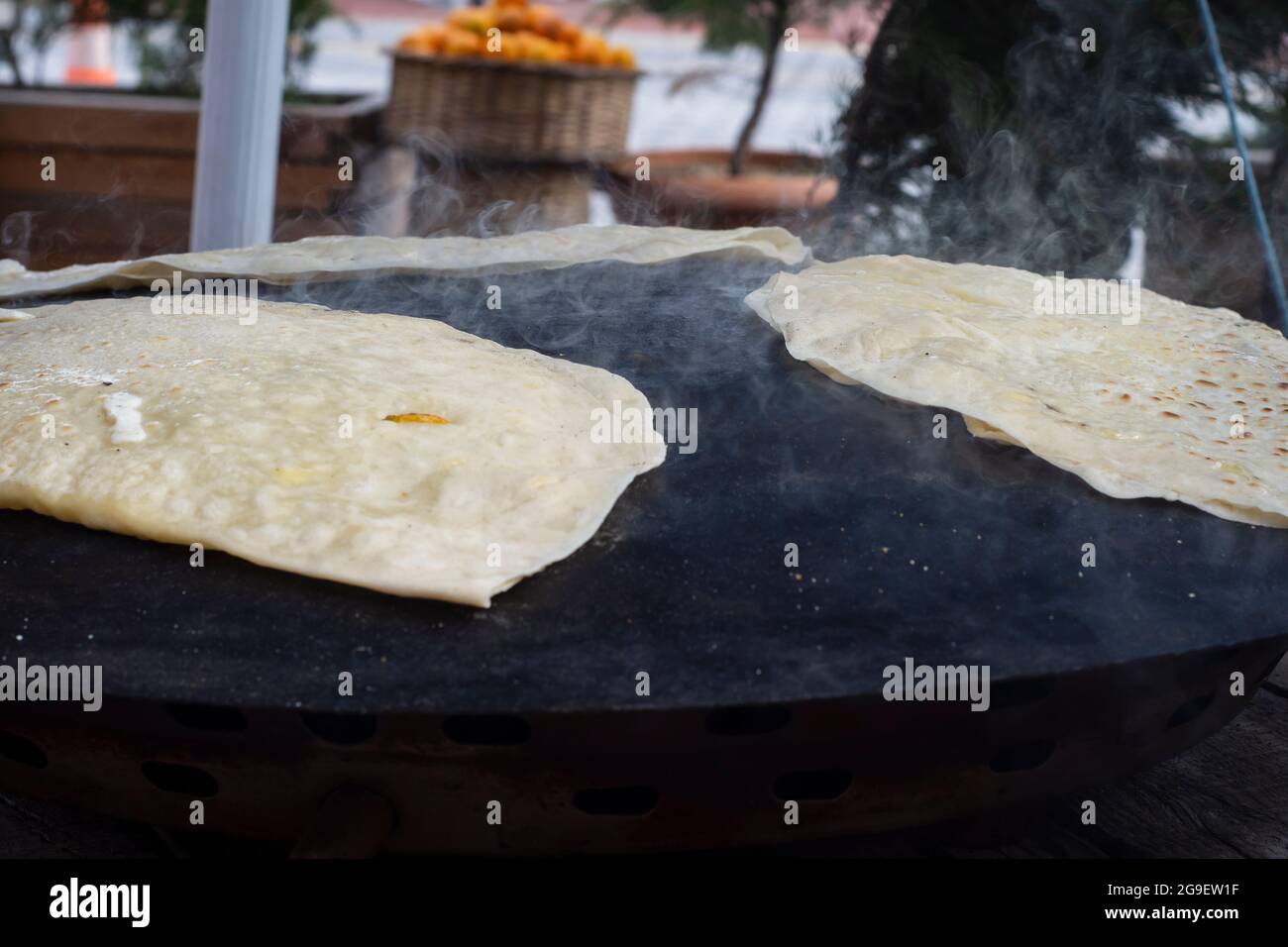 street food: pancake. local woman cooks pancakes on metal sheet, in which she puts cheese, spinach, or potatoes. Selective Focus Pancakes. Stock Photo