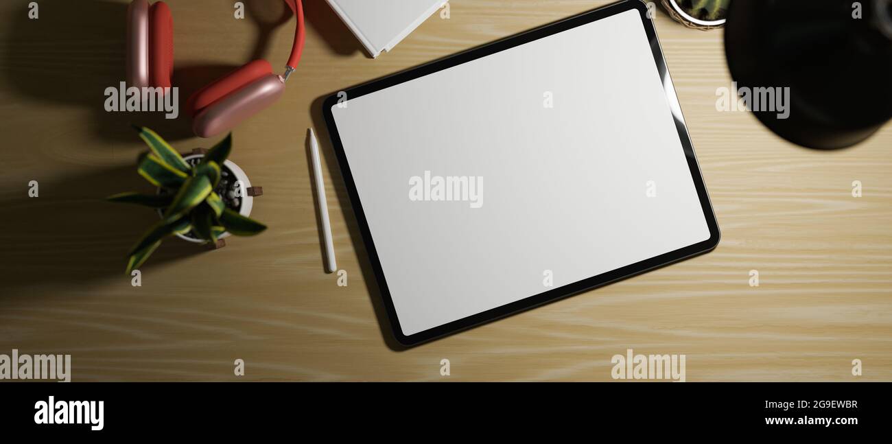 Tablet blank screen on work space with red headphone, house plant and light from table lamp, dark work space, flat lay work space, 3d rendering, 3d il Stock Photo