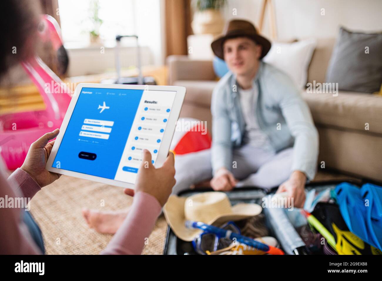 Unrecognizable couple with tablet planning holiday, booking flight. Stock Photo