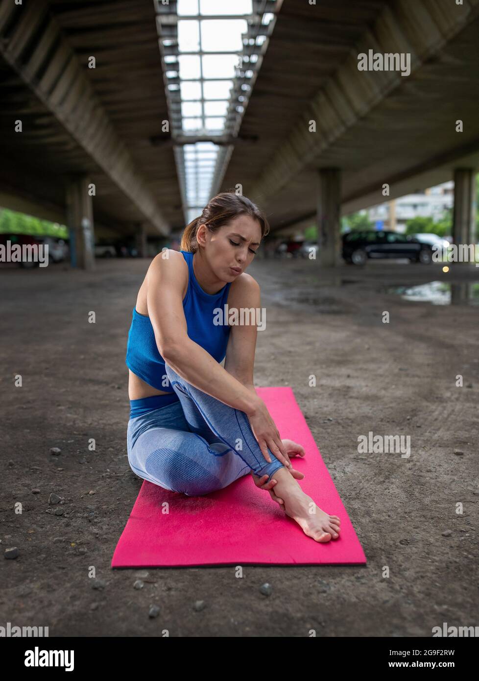 Young athlete holding ankle in pain after exercise. Woman in sportswear