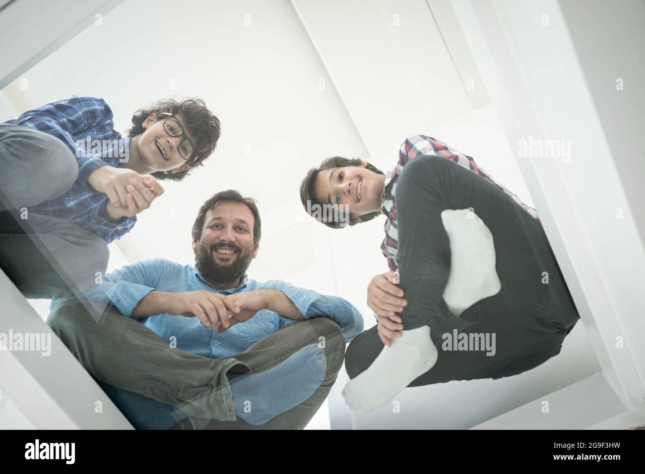 Low angle of father and sons sitting on glass Stock Photo