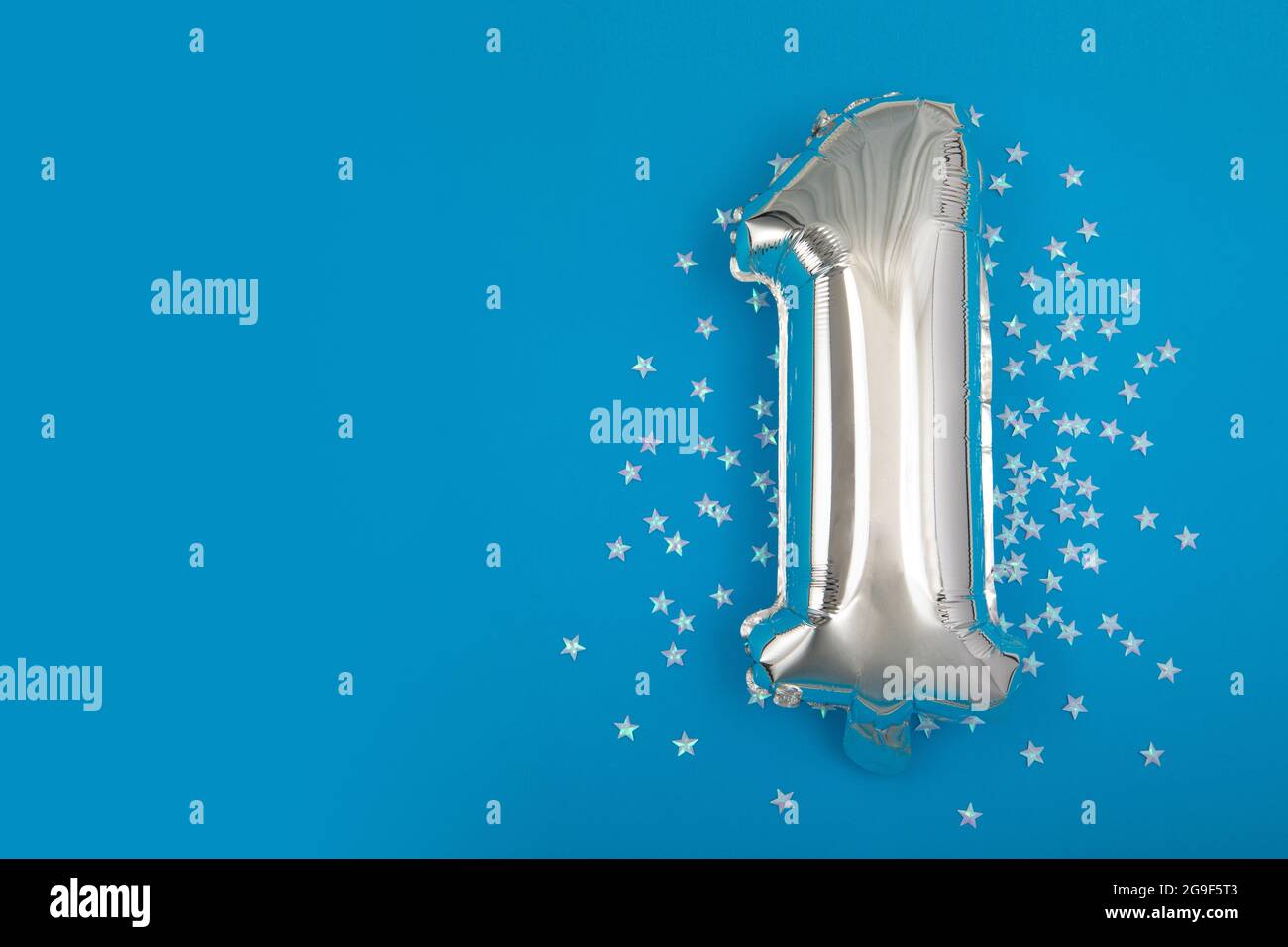 Silver balloon 1 on a blue background with confetti stars. Number One 1. Holiday Party Decoration or postcard concept with top view on blue background Stock Photo