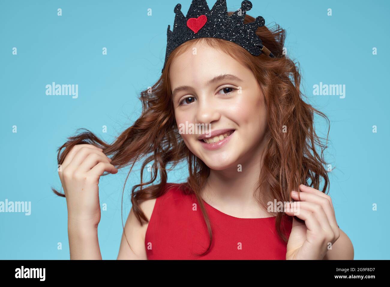 funny girl in a red dress curly hair smile blue background Stock Photo