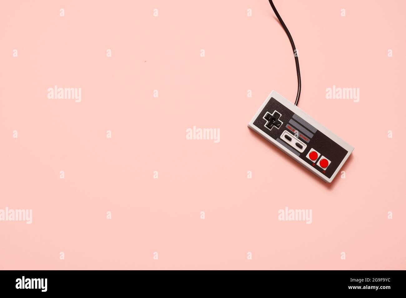 Retro vintage grey game console video game controller on a pastel pink background with copy space and room for text. Stock Photo
