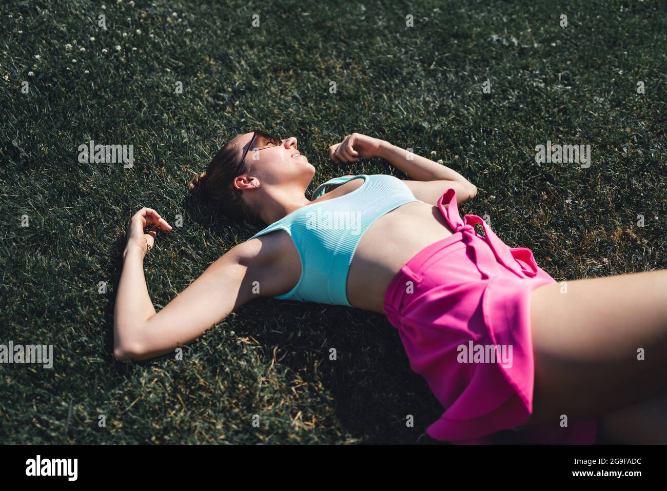 Woman lying down in grass day dreaming in summer. Feeling good optimism. Healthy gorgeous pretty model relaxing in carefree mood. Peaceful rest. Stock Photo