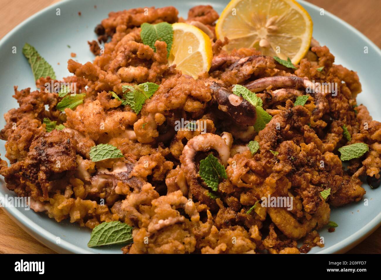 Dish of crispy fried breaded baby octopus served with lemon slices and