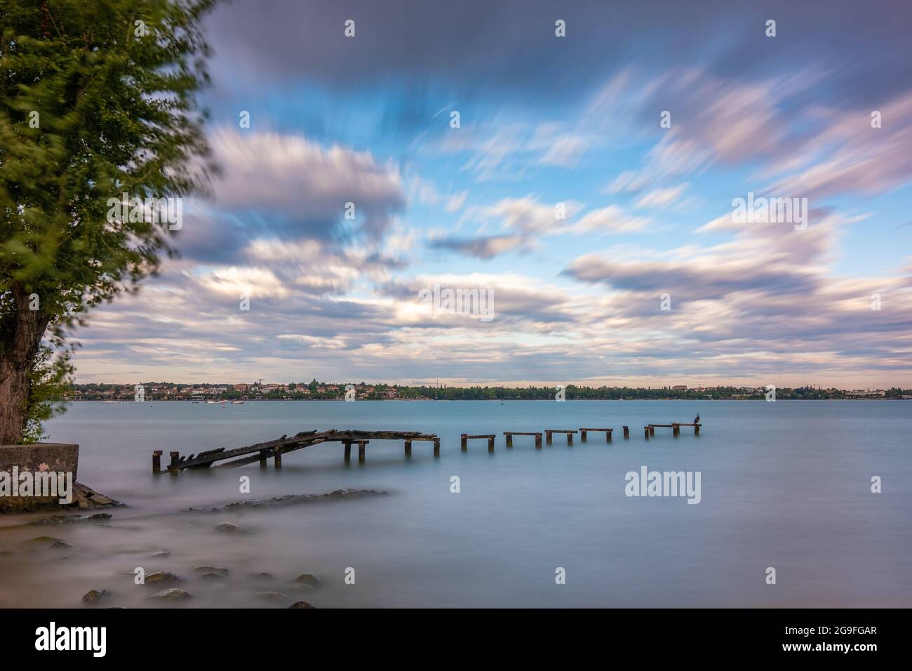 Abandoned wooden pier in lake during sunrise, long exposure Stock Photo